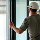 An installer carefully fitting a glass door into its frame